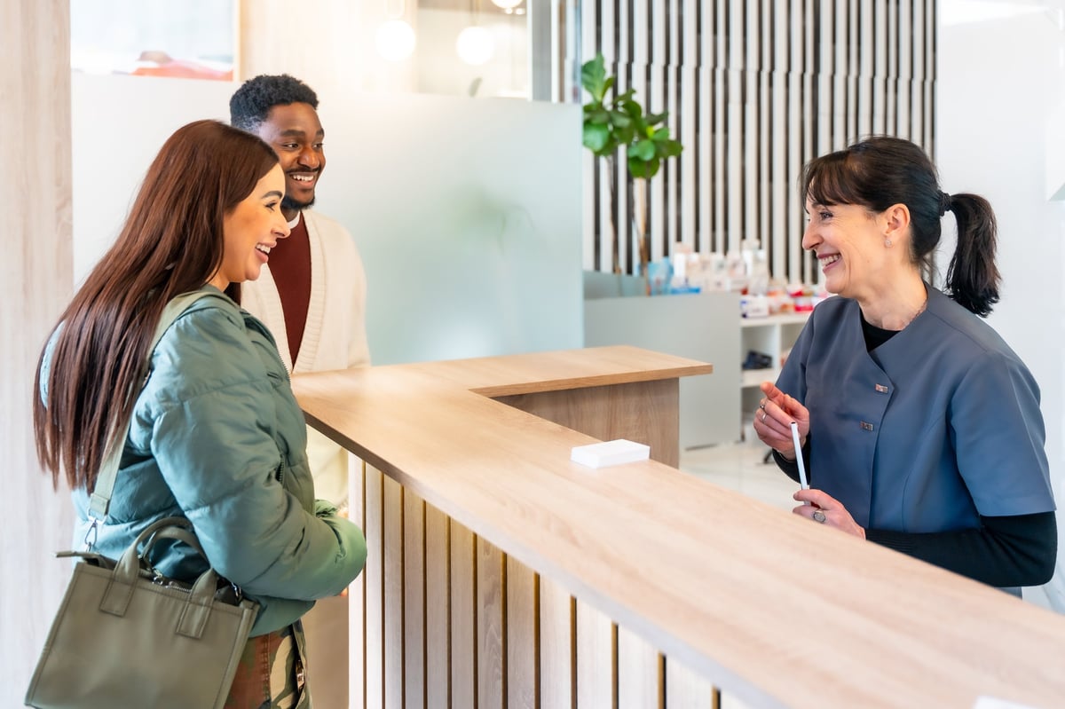 Happy couple at reception desk of modern dental clinic